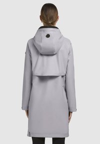 Svijetlosiva vodootporna jakna s velikom kapuljačom, crnim ovratnikom i bočnim džepovima. Karakterizira je elegantna, glatka tekstura i minimalistički dizajn.