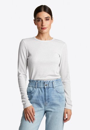 Langärmliges weißes, strukturiertes Oberteil mit Rundhalsausschnitt, kombiniert mit hochgeschnittenen hellblauen Jeans aus Denim mit gerafftem Taillenbund.