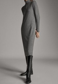 Szara dzianinowa sukienka z długim rękawem, wysokim kołnierzem i zamkiem, zestawiona z czarnymi sk�órzanymi botkami do kolan. Gładka faktura, dopasowany krój.