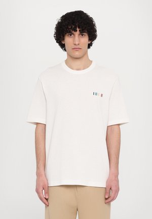 Cream short-sleeve t-shirt made of soft cotton, featuring a round neckline and a small multi-colored striped detail on the left chest.