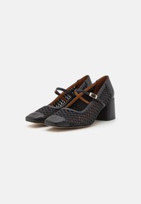 Black heeled shoes with woven texture, featuring a patent toe cap. Adjustable ankle strap and mid-height block heel.