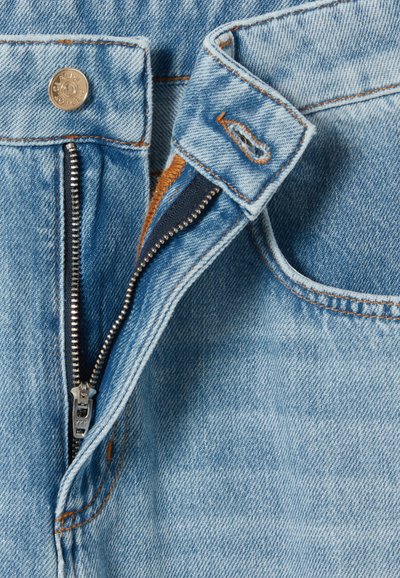 Jean en denim bleu clair avec une fermeture éclair, quincaillerie en métal argenté et surpiqûres orange contrastantes le long de la taille et des bords des poches.