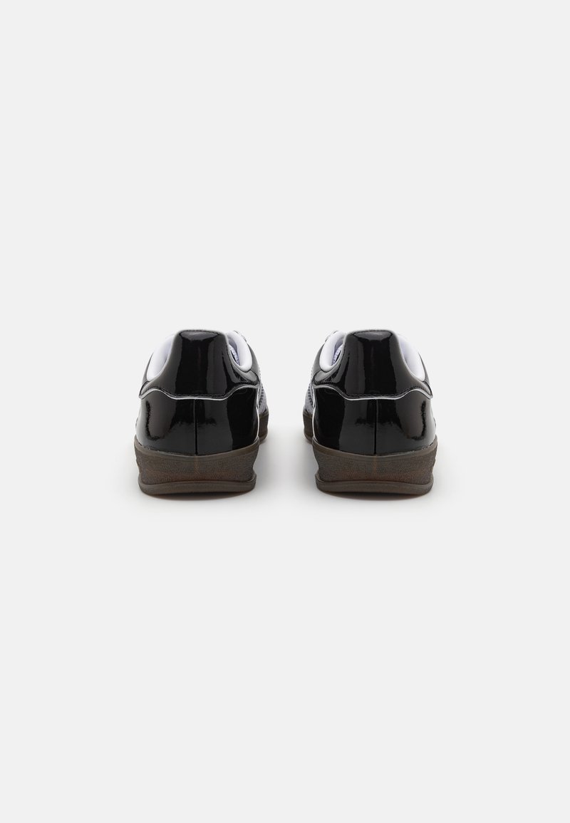 Czarne sneakersy z lakierowanej skóry z białymi akcentami, charakteryzujące się gładką fakturą, niskim profilem i gumowymi podeszwami. Minimalistyczny design bez widocznych elementów metalowych.