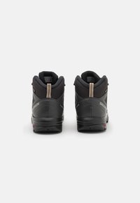 Botas de senderismo negras con un upper texturizado, cuello acolchado y acentos en beige contrastante en el talón. Suela flexible con un patrón de relieve.