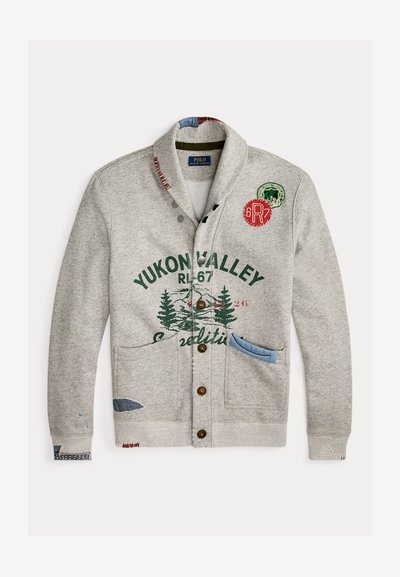 Szary kardigan z kołnierzem typu szal, z grafikami przedstawiającymi zielony las, zapięcie na guziki i niebieskie kieszenie akcentujące. Zawiera dekoracyjne naszywki.