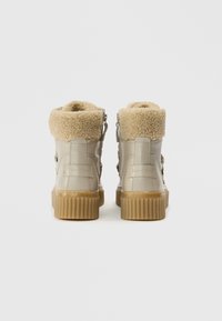 Bottes beiges en cuir synthétique avec col en polaire texturé et semelle en caoutchouc. Comprend une fermeture éclair latérale et un design de semelle superposée.