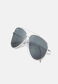 Ochelari de soare aviator cu lentile gri închis, cadru din metal argintiu și pernuțe nazale transparente. Prezintă un design distinctiv cu două punți.