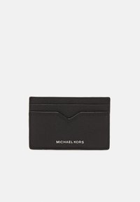 Porte-cartes en cuir noir avec surface texturée, comportant cinq fentes et un accent en chevron. "MICHAEL KORS" embossé en bas.