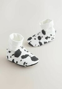 Botines de tela blanca con un estampado de vaca negro. Presentan un suave puño plegable y una suela flexible para mayor comodidad y facilidad de uso.