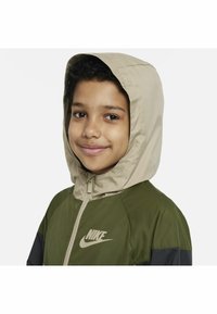 Chaqueta con capucha de Nike que presenta un diseño bicolor con paneles en verde oliva y negro, una capucha marrón claro y un logo sutil en el pecho.