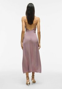 Satin klänning i ljus lavendel, med tunna band och låg rygg. Sömmen faller mitt på vaden. Bärs med beige remsandaler.