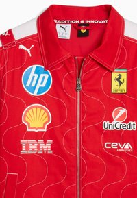 Giacca da corsa rossa con zip, caratterizzata dal logo Ferrari e dai loghi degli sponsor HP, Shell, IBM, UniCredit, CEVA e Puma.