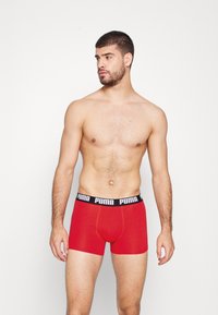 Rote Boxershorts mit einem schwarzen elastischen Bund, der das "PUMA"-Logo trägt. Das Material wirkt weich und hat eine enganliegende Passform.