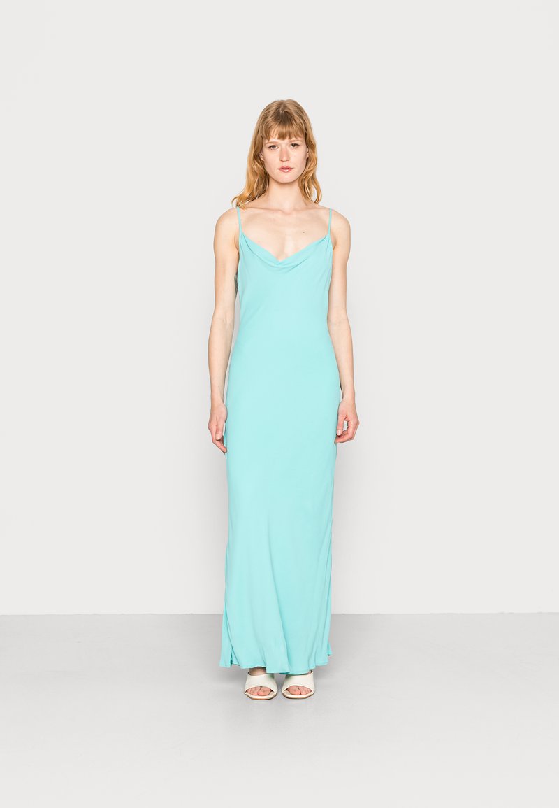 Vestido maxi em turquesa claro, feito de um tecido suave e fluido. Apresenta alças finas e um decote drapeado, criando uma silhueta elegante.