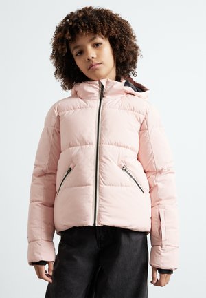 Roze pufferjack met capuchon, voorzien van een front rits en zijzakken met rits. Gestructureerde stof met een doorgestikt patroon. Gedragen over donkere broeken.