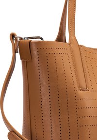 Sac à main en cuir fauve perforé avec une forme structurée, une texture lisse et des accents en métal argenté. Comprend une poignée plate et un design à ouverture supérieure.
