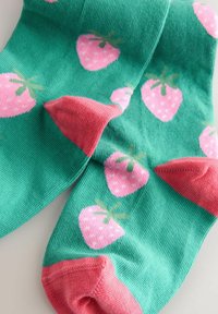 Grüne Socken mit pinkfarbenen Zehen und Fersen, verziert mit pinkfarbenen Erdbeermustern mit grünen Blättern.
