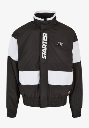 Čierna a biela vetrovka s vysokým golierom, zipsom, elastickými manžetami a rovno strihaným spodkom. Obsahuje veľké biele logo "STARTER".