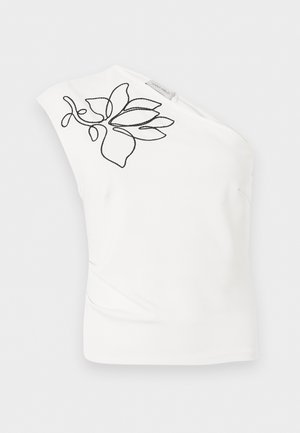 Top bianco monospalla con motivo floreale astratto nero ricamato vicino allo scollo e una piccola etichetta di tessuto del marchio.