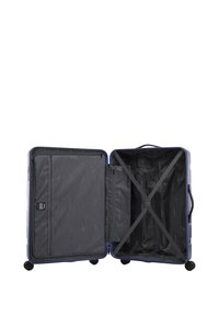 Pevný kufr se skořepinou fialové barvy. Vnitřek má černou výstelku, přihrádky na zip a elastické popruhy pro upevnění věcí.