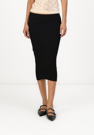 Black ribbed pencil skirt with a mid-calf length, paired with black pointed-toe shoes featuring double buckle accents.