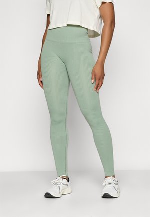 Mintgrønne ribbede leggings med høy midje, kombinert med en kort hvit topp og grå/hvite joggesko.