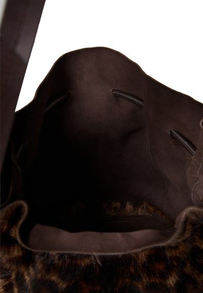 Wnętrze brązowej skórzanej torebki, o miękkiej fakturze, z ciemnym przeszyciem i otwartym designem, ozdobione futrzanym wykończeniem w panterkę.