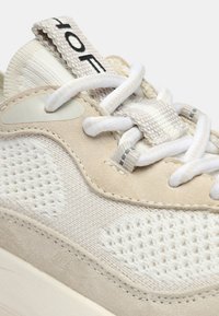 Baskets beige et crème dotées d'une empeigne en mesh, d'accents en daim doux, de motifs texturés et de lacets blancs contrastants. Logo sur la languette.