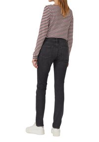 Jeans en denim noir avec une coupe mi-haute, associés à un haut à rayures bordeaux et blanches à manches longues. Le modèle porte des baskets blanches.