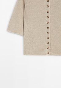 Beige knitted short-sleeve cardigan with a vertical row of small brown buttons on a white background.