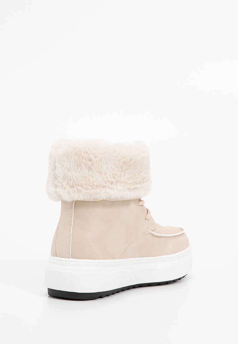 Botte de cheville beige avec bord en fausse fourrure, finition en suède lisse, design à lacets, et semelle plateforme blanche avec un fond noir texturé.