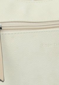 Borsa in finta pelle bianca con una cerniera argentata e un'etichetta piccola. Texture liscia con un leggero motivo a grana. Logo del marchio impresso.