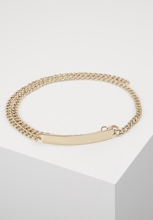 Podwójna złota bransoletka łańcuchowa z gładką prostokątną płytką i zapięciem, przedstawiona na białym tle.