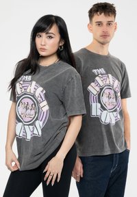 Gray, oversized graphic t-shirts featuring "The Beach Boys" print in pastel colors. Cotton material with a soft, worn texture.