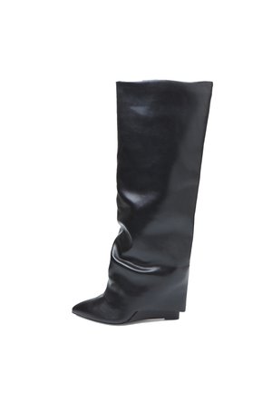 Bota alta de cuero negro con punta puntiaguda y diseño ligeramente caída, con un tacón de cuña bajo sobre un fondo blanco.