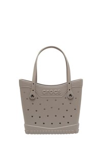 Sac fourre-tout gris clair en matériau semblable à du caoutchouc ; présente un design perforé, des poignées doubles et un logo "crocs" en relief sur le côté.