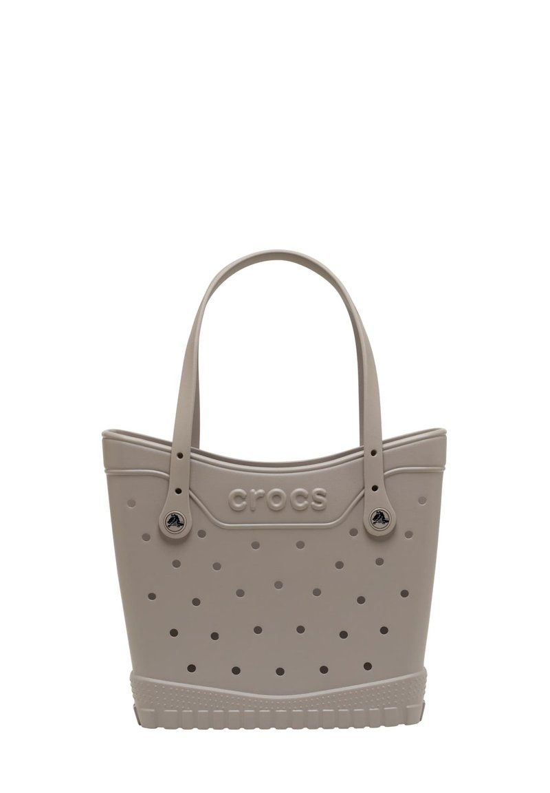 Sac fourre-tout gris clair en matériau semblable à du caoutchouc ; présente un design perforé, des poignées doubles et un logo "crocs" en relief sur le côté.