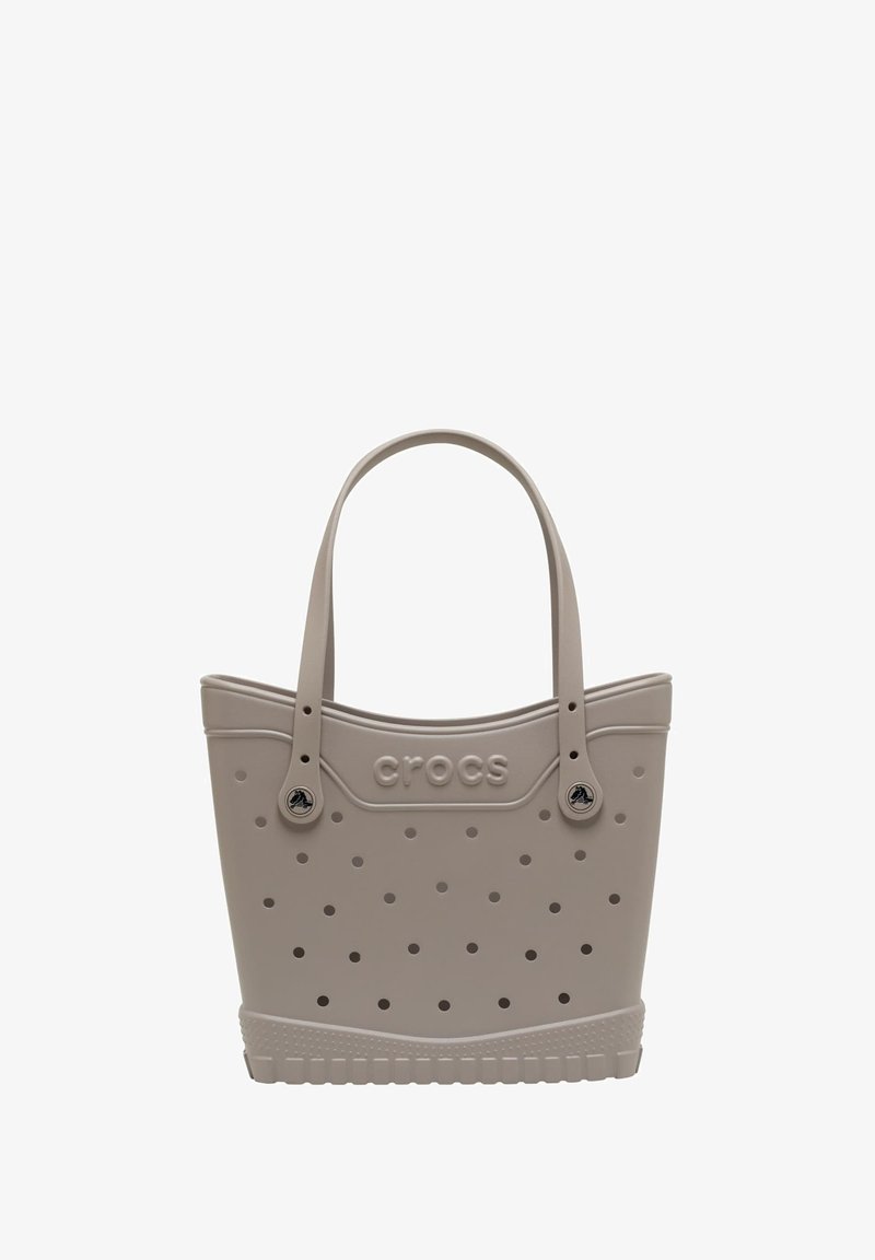 Lichtgrijze tote bag van rubberachtig materiaal; heeft een geperforeerd ontwerp, dubbele handvatten en een reliëf "crocs" logo aan de zijkant.