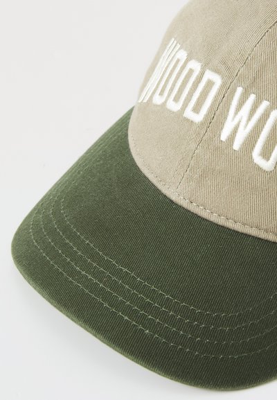 Gorra hecha de tela beige con visera verde. Presenta texto bordado en blanco. Detalles cosidos a lo largo de la visera y la corona.