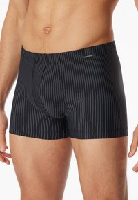 Boxer aderenti a righe nere con un elastico stretch in vita. Presentano sottili righe verticali bianche e un design aderente per comfort e supporto.
