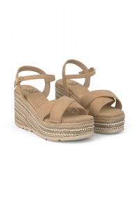 Sandales compensées en toile beige avec des brides croisées, semelle en jute, et accents en perles sur la semelle intermédiaire. Boucle réglable à la cheville.