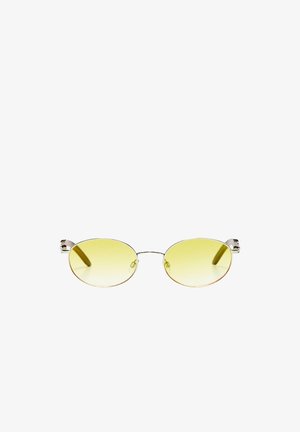 Lunettes de soleil ovales teintées jaune avec fines montures en métal argenté et plaquettes de nez sur fond blanc.
