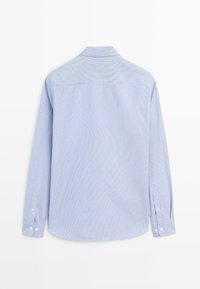 Camicia azzurro chiaro a maniche lunghe con righe bianche verticali, polsini con bottoni, colletto piegato e orlo arrotondato. Il tessuto appare liscio e leggero.