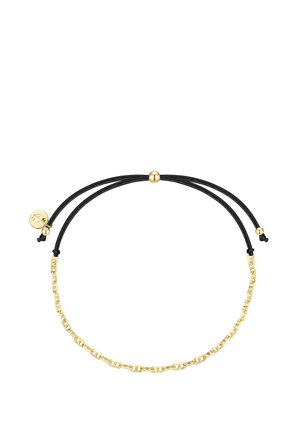 Zelta ķēdes aproce ar regulējamu melnu auklu un mazu apaļu zelta piekari uz vienkārša balta fona.