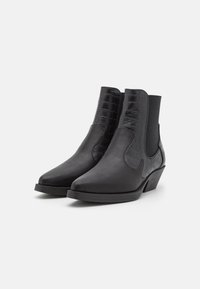 Botas de tobillo negras con punta afilada, panel de cuero texturizado con grabado de cocodrilo, laterales elásticos y tacón bajo en bloque. Acabado liso en general.