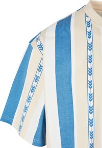 Kortärmad skjorta i beige och blå, med vertikala ränder och ett blommönster. Mjukt bomullstyg med en rundad halsringning.