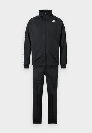 Zwart sportjack met ritssluiting en bijpassende broek, met een wit logo op de borst en merkaccenten langs de mouwen.