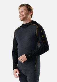 Hooded long-sleeve shirt in dark gray and black, featuring gold stitching and unique sleeve graphics. Made from lightweight, textured fabric.