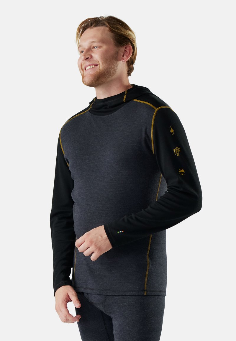 Hooded long-sleeve shirt in dark gray and black, featuring gold stitching and unique sleeve graphics. Made from lightweight, textured fabric.