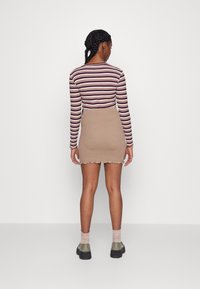 Camisola de manga longa às riscas em roxo e creme, combinada com uma saia justo bege com bainha recortada. Usado com botas de tornozelo e meias.